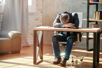 Tired mature businessman working in office