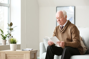 Portrait of elderly man reading book at home