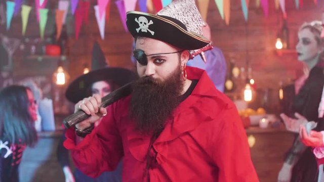 Evil pirate dancing at a fun halloween party with his scary friends. People celebrating halloween in different horror costumes.