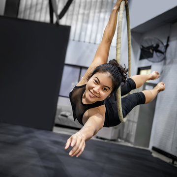 Asian Gymnast Girl Doing Her Gymnastics Performance On Aerial Hoop Or Aerial Ring In Fitness Gym.