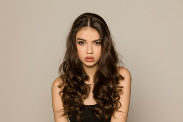 Young woman with makeup and long hair, posing on white background