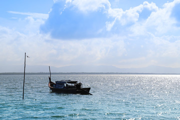 Scenery of local fishery boat, adapted to be touristic boat lie at anchor in Andaman sea with cloudy blue sky background. 