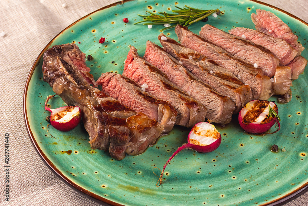 Sticker Juicy medium rare beef steak slices on ceramic plate with herbs spices and salt.