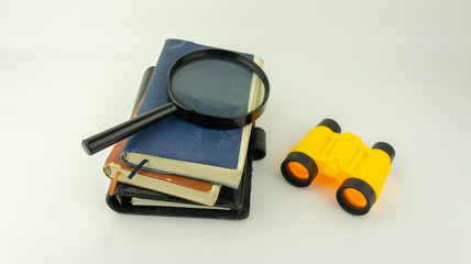 Books,magnifier glass and binocular on white background