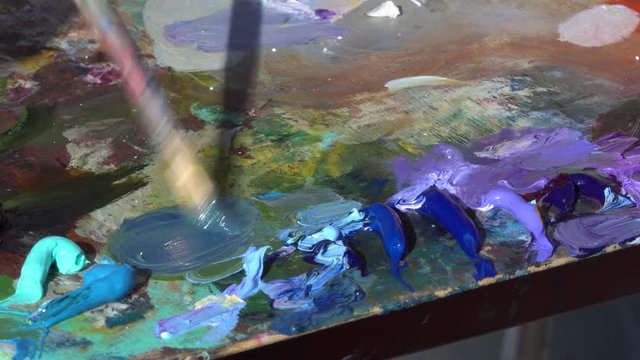 The Artist's Oil Palette. Mixing oil paint for painting. Blue, red, violet, purple colors