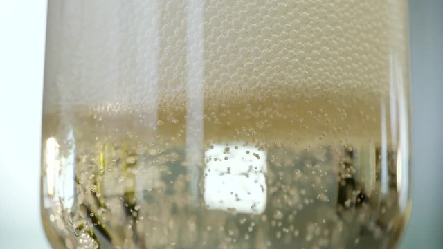 In this close up shot you can see glass being filled with champagne and overfill foam sliding on the glass.