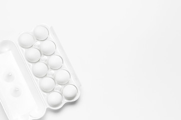 White chicken eggs in white packaging on light background top view flat lay copy space. Eggs in box, natural healthy food and organic farming concept. Creative food minimalistic background, Easter
