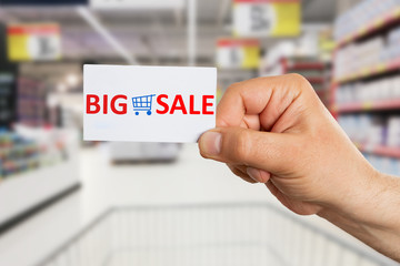 Hypermarket employee presenting big sale text