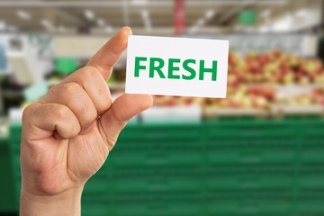 Grocery store employee holding fresh text on paper