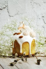 Easter cake in the form of a rabbit on a table, a light table decorated with rabbits and flowers of gypsophila and willow