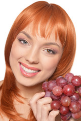 Beautiful redhead young woman with red grapes posing isolated on white background