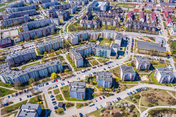 Aerial city view with crossroads and roads, houses, buildings, parks and parking lots.