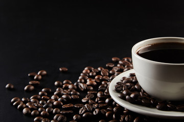 A cu[ of coffee and coffe beans on black background.