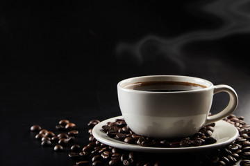 A cu[ of coffee and coffe beans on black background.