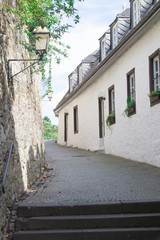 Fototapeta na wymiar narrow street with ruin brick wall and white small house in Stolberg, Germany