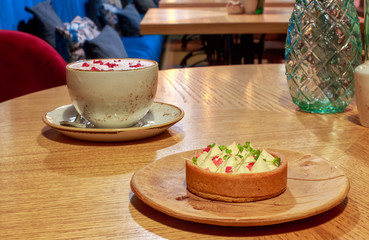 Cup raspberry Raf coffee in a vegetarian restaurant. Pink coffee based on vegetable milk with dried raspberries on top. Tartlet made of cornmeal and almond flour with coconut milk vanilla and anise.