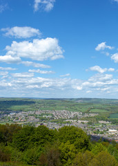 Fototapeta na wymiar Small English town viewed from hillside set in landscape with blue sky and clouds