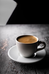 Black coffee with foam in a cup, an aromatic hot drink.