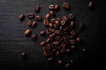 Coffee beans. Roasted coffee fries on a dark table.