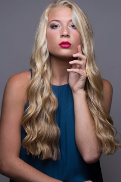 Portrait of blond woman with red lips posing with one hand on vace