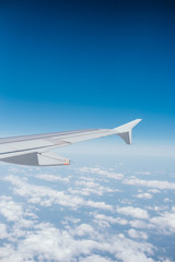 Wing of the airplane with the view of beautiful blue sky and clouds.