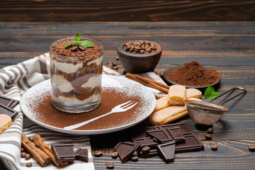 Classic tiramisu dessert in a glass on wooden background