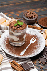 Classic tiramisu dessert in a glass on wooden background
