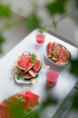 Fresh red smoothie in a glass with sliced pieces of watermelon on table.