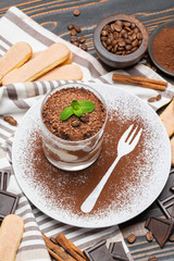 Classic tiramisu dessert in a glass on wooden background