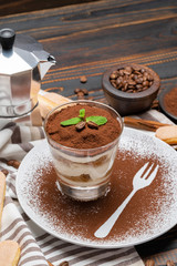 Classic tiramisu dessert in a glass on wooden background