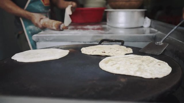 4k Chapati Indian bread making process turning on flat hot frying surface, hands turning chapatis with spatula