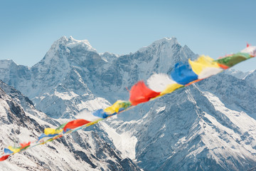 Everest trekking and hiking. Mountains of Nepal. Mountain in focus. Nepalese prayer flags are...