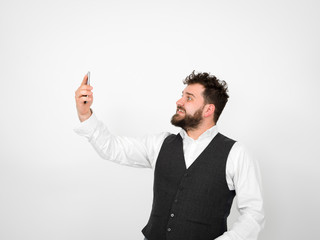 young man with black beard is posing and looking at his smartphone in front of white background with different emotions