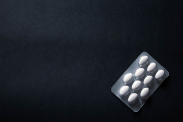 pills in blister on black background with copyspace