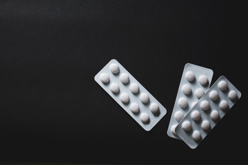 pills in blister on black background with copyspace