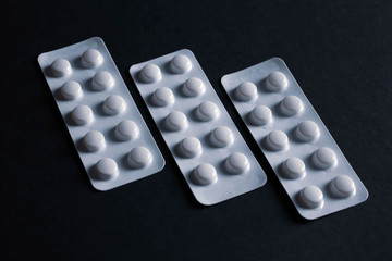 pills in blister on black background with copyspace