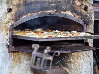 The cook prepares food on an outdoor antique wood-burning oven