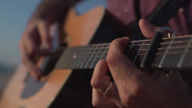 Man Playing and tuning acoustic Guitar Close Up shot side angle shot outdoor