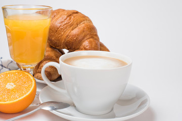 Breakfast coffee with croissants and orange juice on a white background. Latte on a saucer and cellular cotton towel