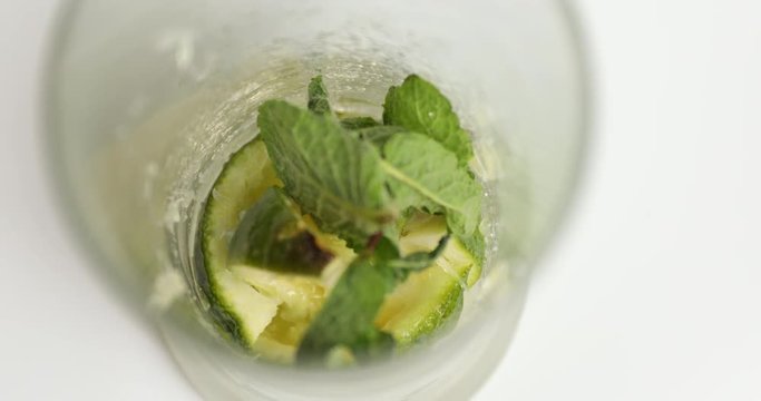 Putting mints in glass cup with limes to make Mojito cocktail