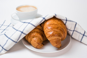 Breakfast coffee with croissants and checkered towel on a white background. Latte on a saucer