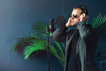 Close up of a man singer in a headphones recording a song in a home studio