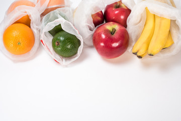 Life in the style of zero waste. Fruit orange, apple, avocado, banana in eco bag on a white background. Replacing the plastic bag. Without garbage.