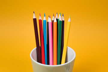 Fototapeta premium Back to school. Children's creativity. Color pencils in a glass on a yellow background