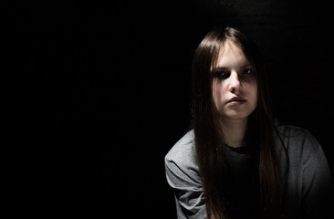 portrait of young teenager brunette girl with long hair in the Gothic style on a black background with copy space