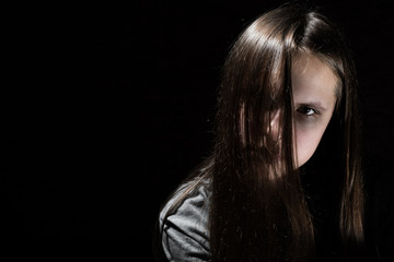 portrait of young teenager brunette girl with long hair in the Gothic style on a black background with copy space