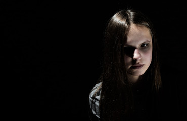 Fototapeta na wymiar portrait of young teenager brunette girl with long hair in the Gothic style on a black background with copy space