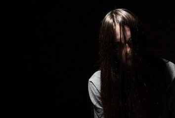 portrait of young teenager brunette girl with long hair in the Gothic style on a black background with copy space