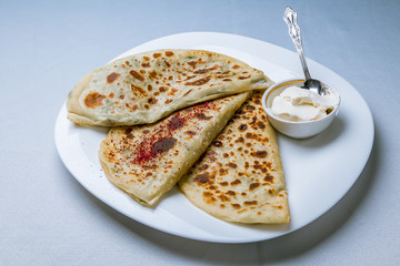Qutabs with sour cream  on white plate