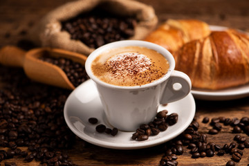 A cup of cappuccino with coffee bean as background.